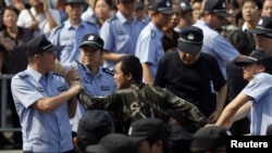 Police officers arrest a protester during a protest against plans to expand a petrochemical plant in Ningbo, Zhejiang province, China, October 27, 2012. 