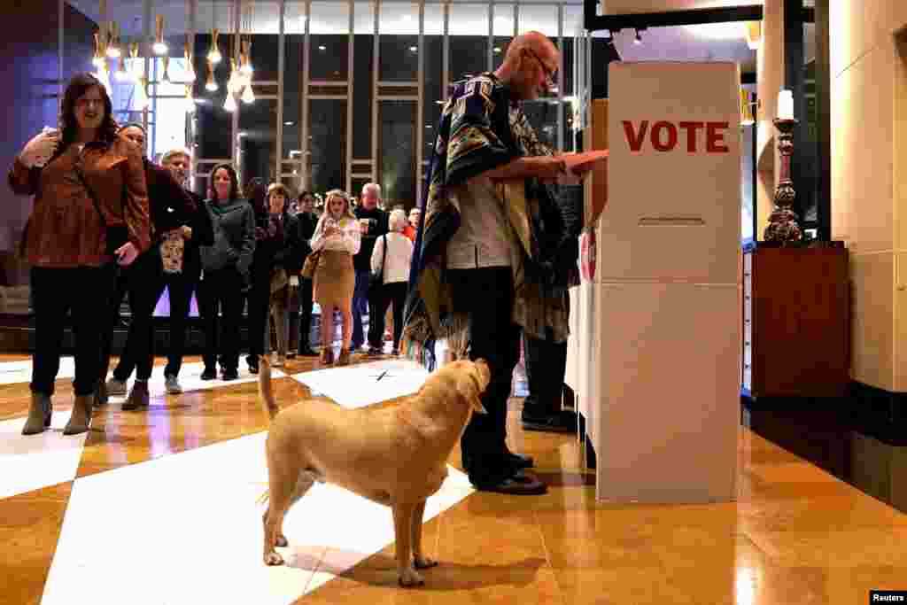 Eddie Craig Monarch reviews his ballot while his dog Sherlock waits at a polling place on Super Tuesday in Oklahoma City, Oklahoma, March 3, 2020.