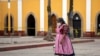 Una mujer indígena con una máscara protectora camina cerca del cementerio en medio de la nueva pandemia de coronavirus en Quetzaltenango, Guatemala, el sábado 8 de agosto de 2020.