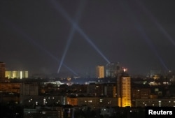Ukrainian service personnel use searchlights as they search for drones in the sky over the city during a Russian drone strike in Kyiv, Aug. 29, 2024.