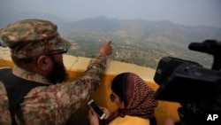 FILE - A Pakistan army officer points out the Indian forward area posts to journalists at Bagsar post on the Line of Control that divides Kashmir between Pakistan and India, Oct. 1, 2016.