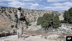 FILE - A Lebanon Hezbollah fighter carries his weapon as he stands in Khashaat, in the Qalamoun region, May 15, 2015. 