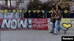 Mujeres caminan junto a un graffiti que apoya la liberación de los rehenes que han sido retenidos en Gaza desde el mortal ataque del 7 de octubre de 2023, en Tel Aviv, Israel, el 18 de febrero de 2025. 