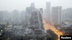 FILE - A building crumbles during a controlled demolition to make way for a new commercial center in Xi'an, Shaanxi province, China.