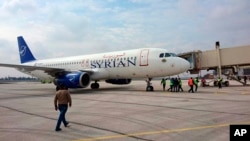 This photo released by the Syrian official news agency SANA, shows a Syrian commercial plane carrying Syrian officials and journalists after it landed at Aleppo airport, Syria, Feb. 19, 2020. 