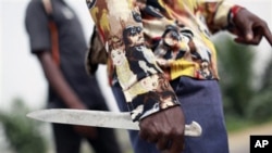 A rebel fighter holds a knife as he stands watch for security forces on a street in the Abobo neighborhood of Abidjan, Ivory Coast. Security forces loyal to Ivory Coast's incumbent leader fired volleys of gunshots, leaving at least four people dead after