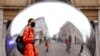 A person wearing a face mask is reflected in an art work entitled "A=V" by Ben Cullen Williams, amid the coronavirus outbreak, in Covent Garden, London, Britain.