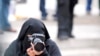 FILE - A burqa-clad female reporter takes photos of protesters at a rally.