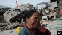 2013年4月20日(星期六)，中国四川省雅安市芦山县发生里氏7级强烈地震。一名妇女在看她家遭受地震损坏后的悲痛情况。