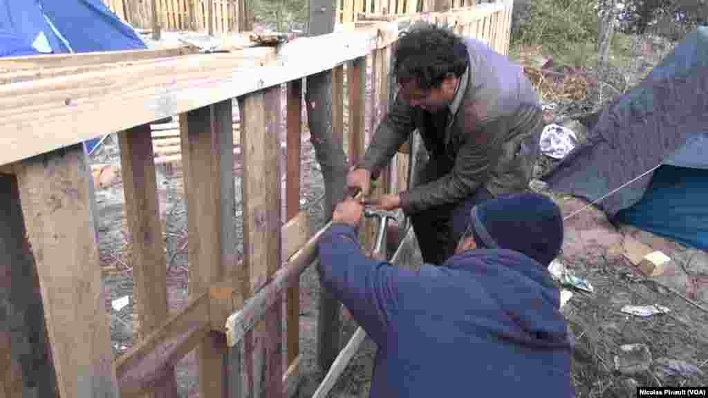 Two migrants building a house in the "Jungle" in Calais, France (Nicolas Pinault/VOA)