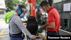 Marlene de Abreu llena el tanque de su moto en una gasolinera en Caracas. 7 de junio de 2020.