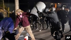 A Portland police officer shoves a protester as police try to disperse the crowd in front of the Multnomah County Sheriff's Office early in the morning on Aug. 8, 2020 in Portland, Ore.