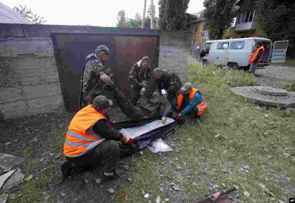 Qutqaruvchilar va rossiyaparast isyonchilar otishmada halok bo'lgan odamning jasadini olib ketmoqda, Donetsk, sharqiy Ukraina, 1-oktabr, 2014-yil.