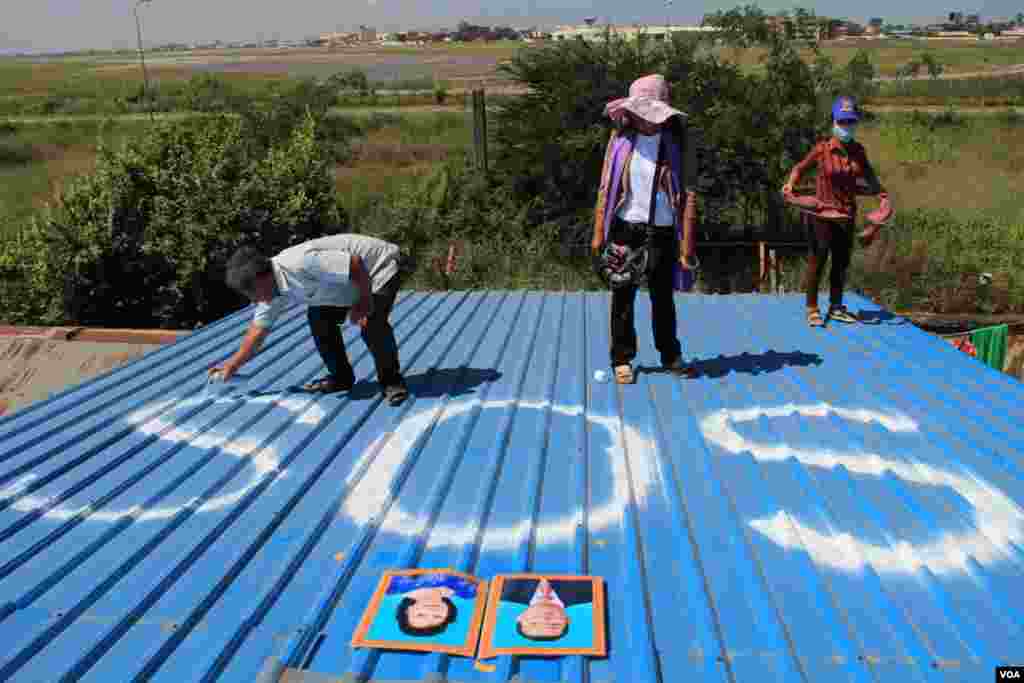 People in Tropeang Lavear display SOS messages on their roofs, which lies in the flight path to Phnom Penh international airport, Cambodia, November 13, 2014. (Nov Povleakhena/VOA Khmer)