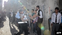 FILE - A man carries an injured child after four rockets fired from Syria slammed into the southern Turkish town of Kilis, killing four Syrians — including three children — in a cross-border strike, April 18, 2016.