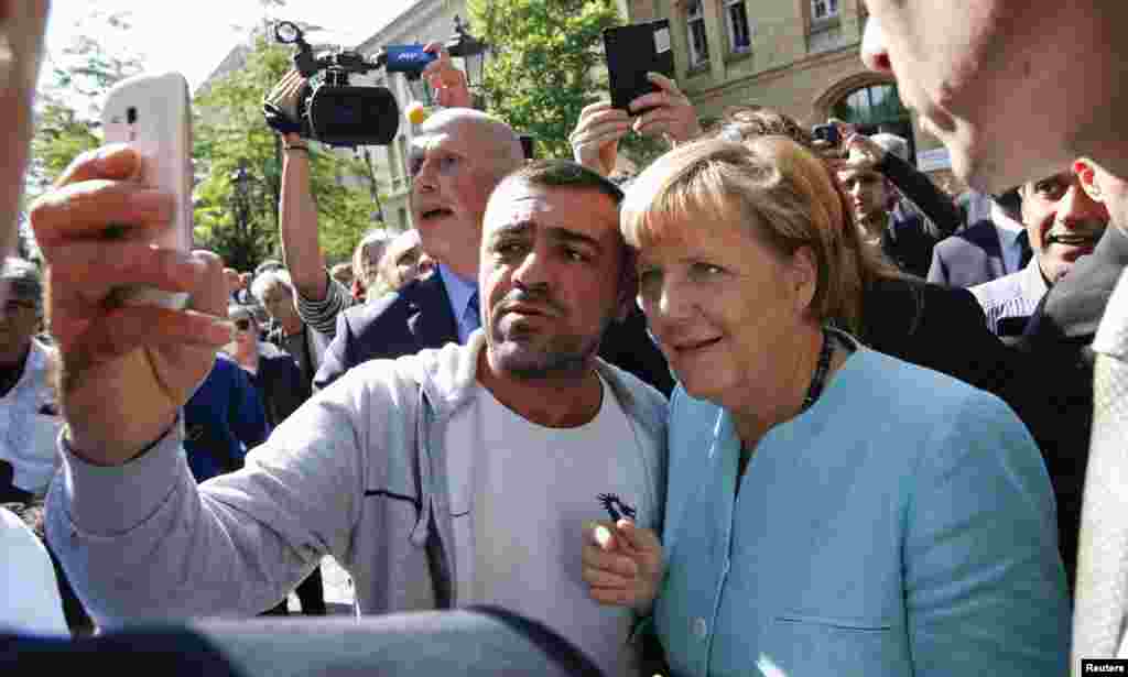 German Chancellor Angela Merkel visits a refugee camp near the Federal Office for Migration and Refugees at Berlin's Spandau district. A migrant takes a selfie with Merkel outside the refegee camp.