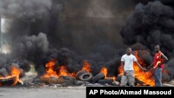 Deux jeunes ivoiriens se tiennent devant une barricade en feu érigée dans le quartier de Koumassi à Abidjan lors des affrontements entre les partisans du candidat de l'opposition Alassane Ouattara et ceux du président sortant Laurent Gbagbo qui refusent de céder le pouvoir, Abidjan, Côte d'Ivoire, 6 décembre 2010.