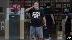 A Chinese man looks out near a Huawei store promoting 5G services in Beijing, as the United States and Britain have put on a show of unity against the Chinese telecoms giant Huawei.