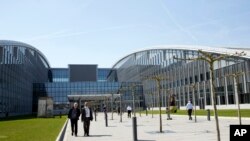 Para pengunjung berjalan di luar markas NATO yang baru di Brussels, 19 April 2018.