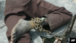 FILE - A patient at a home for the mentally ill is chained to a table in Monrovia, Liberia, Aug. 29, 2003.