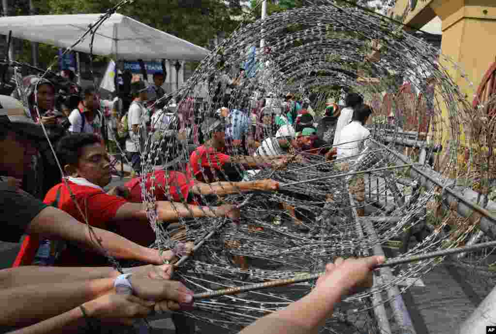 Filipino activists pull barb wired fence as they try to go near the Malacanang presidential palace in Manila, Philippines, Monday April 28, 2014 during a rally to oppose the Enhanced Defense Cooperation Agreement between the Philippines and U.S. The U.S.
