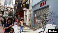 FILE - People walk past a vandalized store in Causeway Bay district, in Hong Kong, Oct. 8, 2019. 