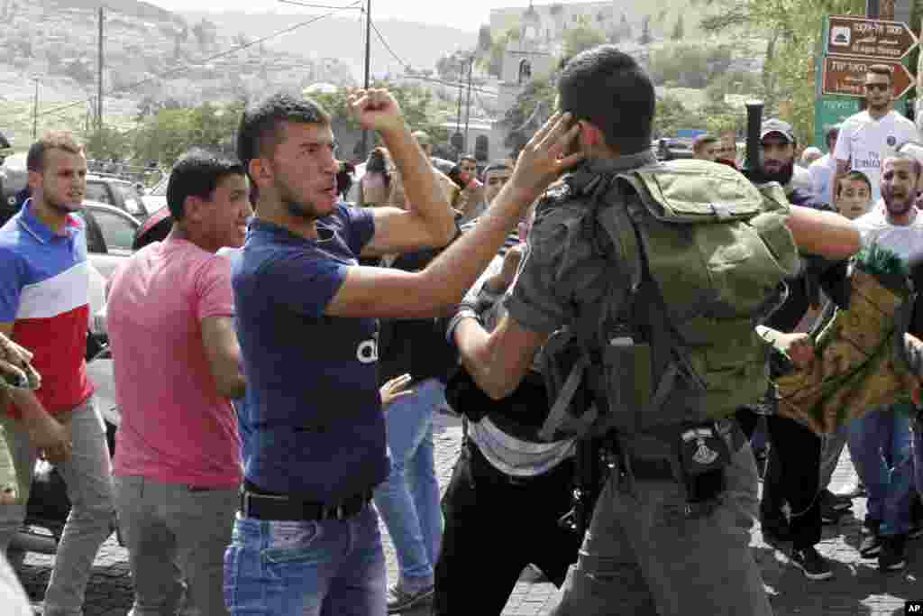 An Israeli border policeman exchanges blows with a Palestinian man during a confrontation after Friday prayers outside the Old City in Jerusalem, Oct. 2, 2015. 