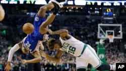 A player for the Philadelphia 76ers falls as he tries to block a shot by Boston Celtics' player in this 2017 NBA basketball game. (AP Photo/Elise Amendola)