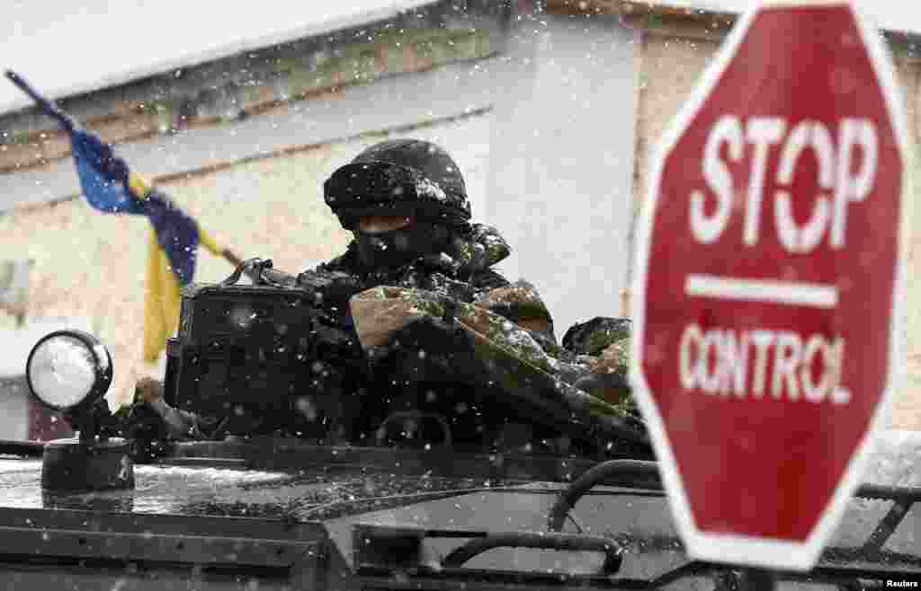 Seorang pria bersenjata, dipercaya sebagai seorang tentara Rusia, berdiri di luar pangkalan militer Ukraina di Perevalnoye, dekat Simferopol 16 Maret 2014.