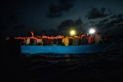 Dozens of African migrants wait to be assisted by a team of aid workers of the Spanish NGO Open Arms, after spending more than 20 hours at sea, in the Central Mediterranean sea, Sept. 8, 2020.
