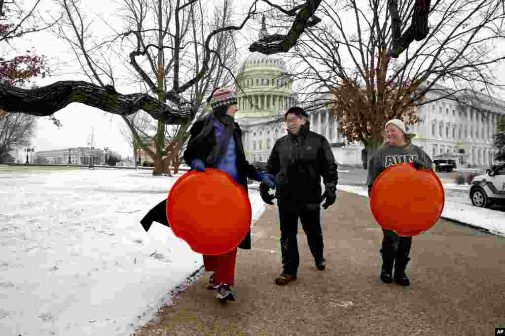 Jessica Pate, Sherri Sheu tare da Anna Foresee wadanda suka kasanshe mazamna unguwar dake kusan Ofishin shugaban kasar wato Capitol Hill dake birnin Washington DC na taimakawa waken kawar da dosar kankara, Alhamis 04, janairu 2018. 