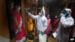 A health worker checks the body temperature of residents during a free medical checkup in a slum in Mumbai, India, the fourth hardest-hit country by the COVID-19 pandemic in the world after the U.S., Russia and Brazil, June 28, 2020.