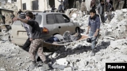 Residents carry an injured woman on a stretcher in a site hit by airstrikes in the rebel-controlled area of Maarat al-Numan town in Idlib province, Syria, Jan. 9, 2016.