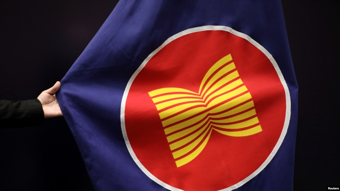 A worker adjusts an ASEAN flag at a meeting hall in Kuala Lumpur, Malaysia, October 28, 2021. REUTERS/Lim Huey Teng