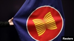 Seorang pekerja membereskan letak bendera ASEAN di aula pertemuan di Kuala Lumpur, Malaysia, 28 Oktober 2021. (Foto: REUTERS/Lim Huey Teng)