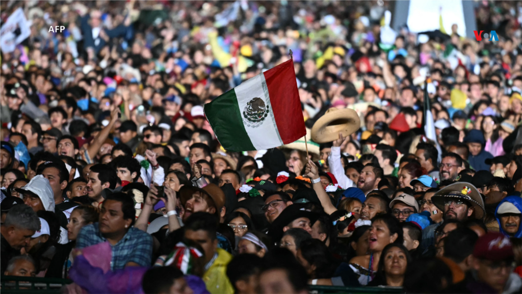 Un hombre sostiene una bandera mexicana, mientras la gente asiste a la ceremonia del 'Grito de Independencia' que marca el inicio de las celebraciones del Día de la Independencia en la Plaza El Zócalo de la Ciudad de México.