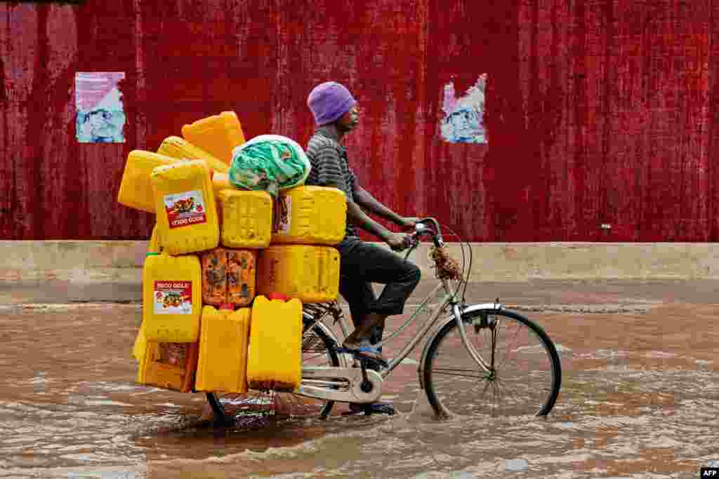 Seorang pria mengendarai sepedanya melalui jalanan yang tergenang banjir di Dar es Salaam, Tanzania.