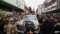 Mourners surround a car carrying the coffins of Iranian Gen. Qasem Soleimani and Iraqi paramilitary chief Abu Mahdi al-Muhandis, killed in a U.S. airstrike, during their funeral procession in a Shiite pilgrimage district of Baghdad.