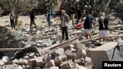 Warga berjalan di antara puing-puing bangunan yang hancur oleh serangan udara koalisi pimpinan Saudi di Sana'a, Yaman (2/2). (Reuters/Mohamed al-Sayaghi)