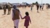 ARCHIVO - Un hombre camina con un niño por la aldea Doña Ana de Fort Bliss, donde se alojaban refugiados afganos, en Nuevo México, el 10 de septiembre de 2021.