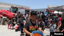 Sejumlah warga Palestina membawa makanan yang dimasak oleh dapur relawan di Khan Younis di tengah kurangnya bantuan masuk ke Jalur Gaza, pada 19 Juni 2024. (Foto: Reuters/Hatem Khaled)