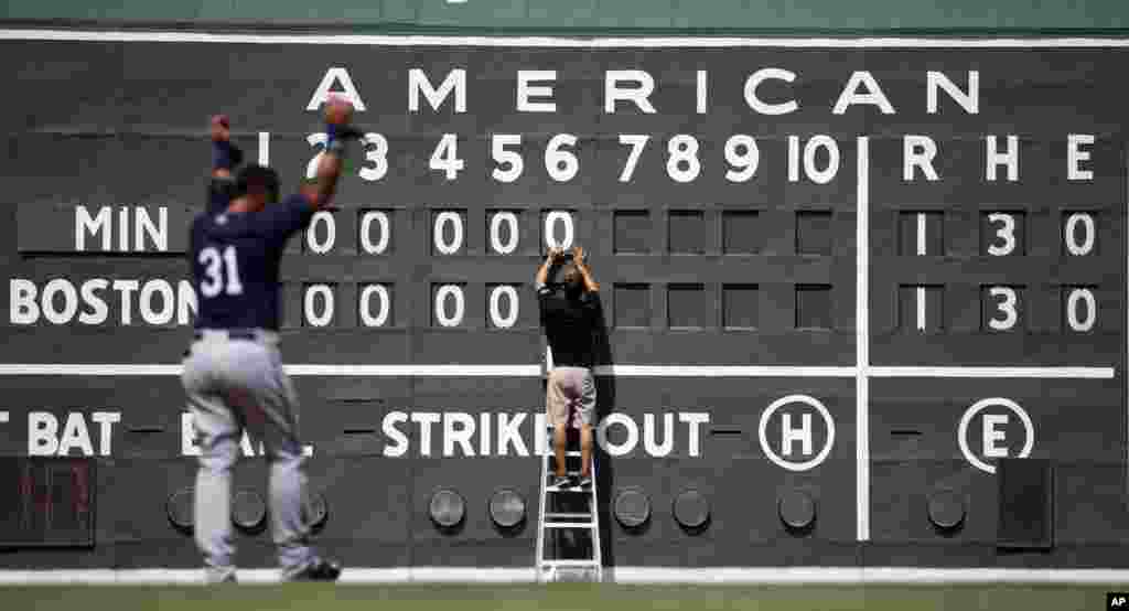 Anak magang Boston Red Sox, Tim Batesole mengganti papan skor manual dalam inning ke-enam latihan baseball musim semi melawan Minnesota Twins di Fort Myers, Florida, 18 Maret 2015.
