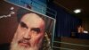 FILE - A girl walks past a poster of Ayatollah Ruhollah Khomeini, at a mosque where he made speeches, in northern Tehran, Iran, Jan. 22, 2019.