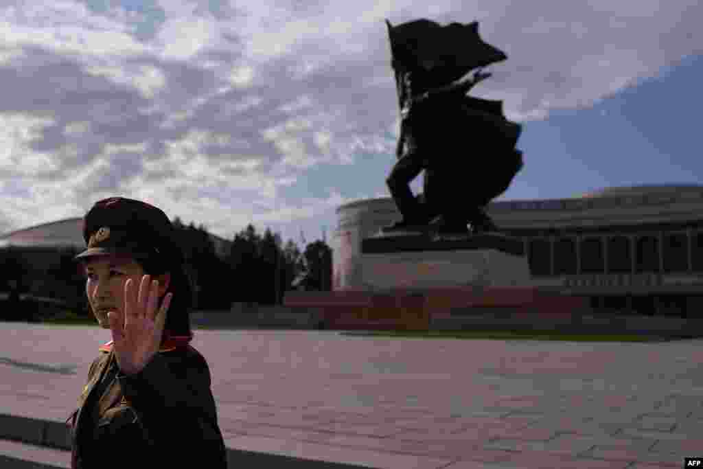 A uniformed tour guide gestures to tourists outside the War Museum in Pyongyang, North Korea. North Korea is gearing up for a lavish celebration marking the 70th anniversary of its ruling Workers' Party on Oct. 10.