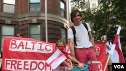 Lauren Barysevich, 5, with her father Yauheni Barysevich who was born in Belarus, at the Aug. 23, 2020 demonstration in Washington in support of Belarusians. Lauren made the small flag, the big flag was sewn by her mother. (Natalie Liu/VOA)