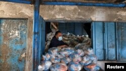 Un trabajador palestino observa mientras prepara bolsas de alimentos en un centro de distribución de ayuda dirigido por la Agencia de Obras Públicas y Socorro de las Naciones Unidas (UNRWA), en un campamento de refugiados en la ciudad de Gaza.