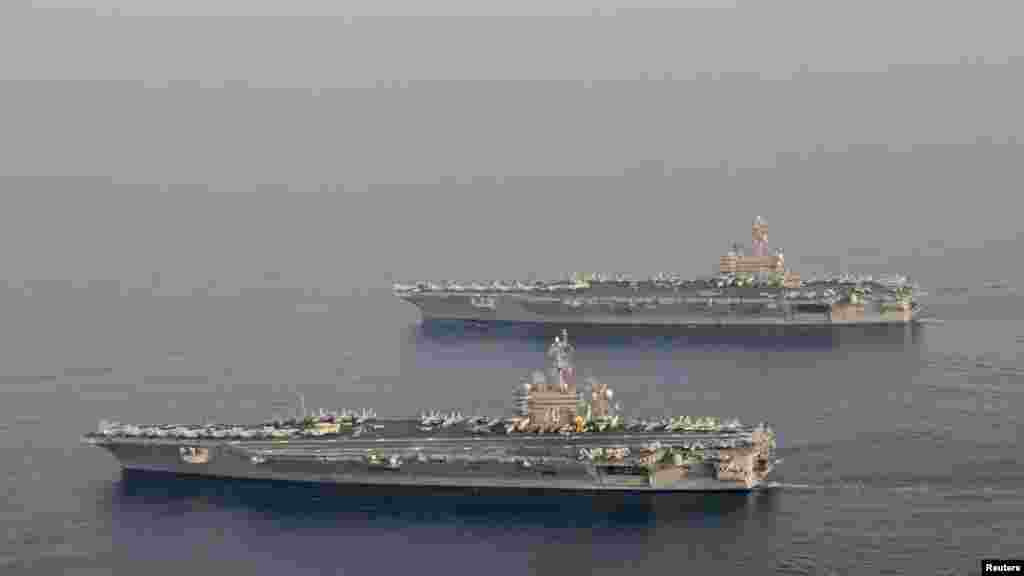 The U.S. Navy aircraft carrier USS Carl Vinson (CVN 70), bottom, is seen relieving the USS George H.W. Bush in the Arabian Gulf, Oct. 18, 2014. The George H.W. Bush will soon depart for its homeport at Norfolk, Va., and Carl Vinson will take over support of maritime security operations, strike operations in Iraq and Syria.