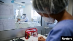 Trabajadores médicos atienten a un paciente de coronavirus en una unidad de cuidados intensivos del Hospital das Clinicas en Porto Alegre, Brasil, el 14 de enero de 2022.