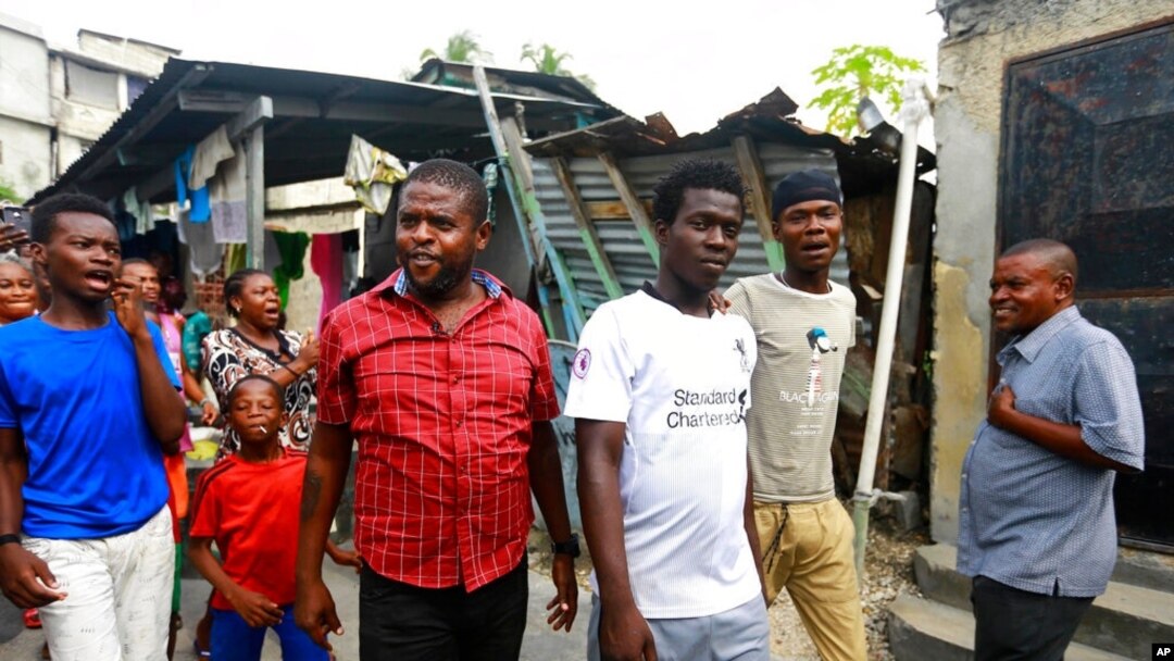 FILE - Barbecue, whose real name is Jimmy Cherizier, center left, walks as residents chant "Barbecue for life" in his neighborhood in Lower Delmas, a district of Port-au-Prince, Haiti, May 24, 2019.
