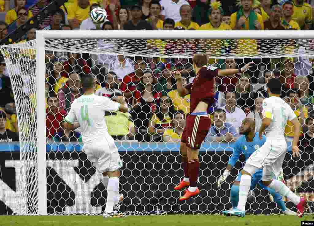 Russia's Alexander Kokorin heads the ball into the net as Algeria's Rais Mbolhi (goalkeeper), Essaid Belkalem (4) and Rafik Halliche (5) watch at the Baixada arena in Curitiba, June 26, 2014.